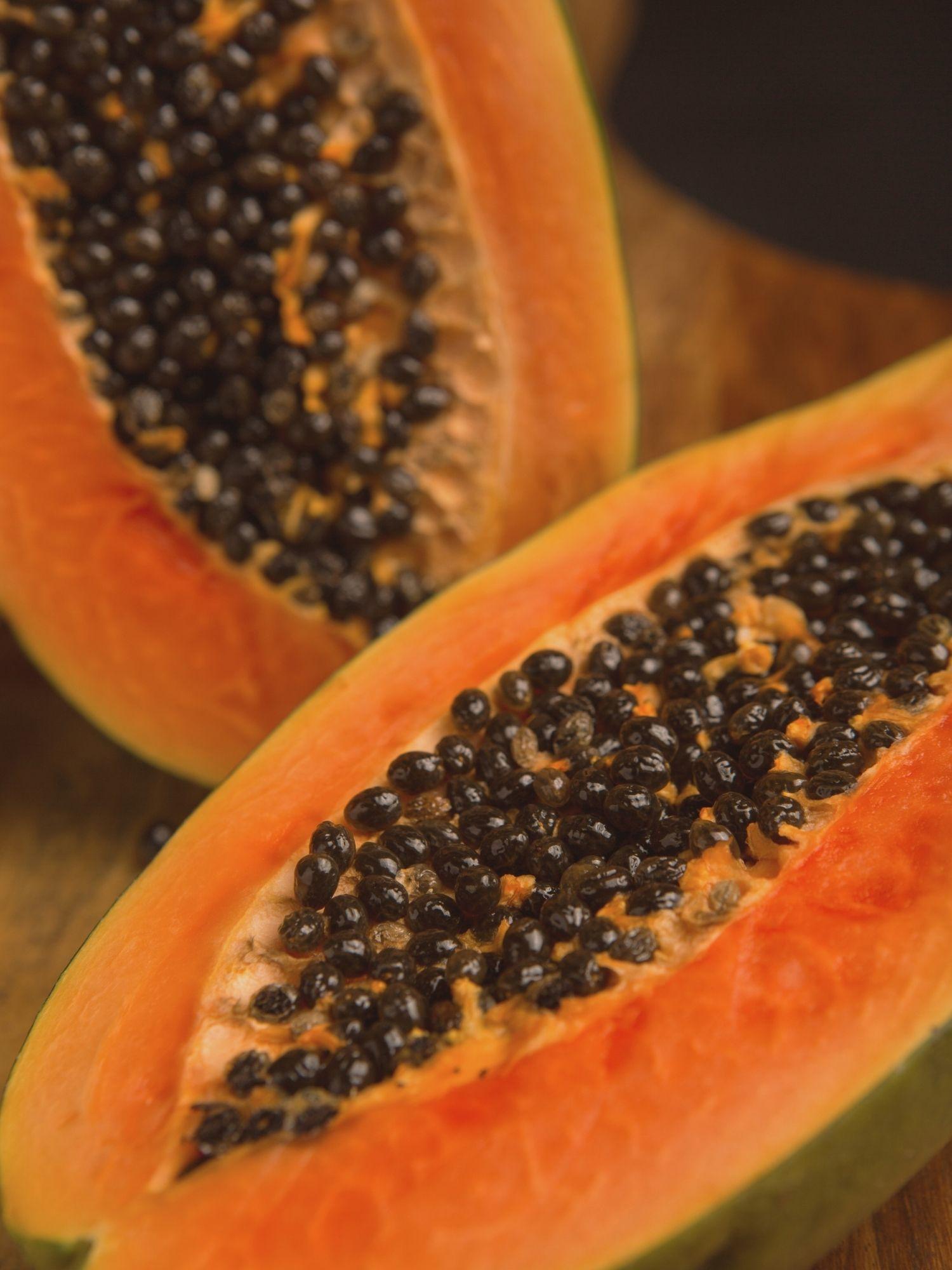 Papayafrucht mit Papayasamen aufgeschnitten auf Holztisch | Naturstoff